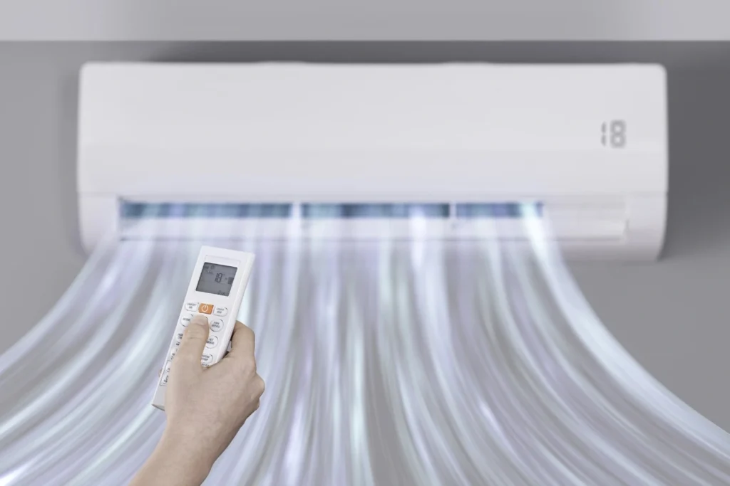 A technician is holding a black tablet to take a picture or video of the internal components of a metal furnace or HVAC unit. The tablet screen shows a close-up of the blower fan. The technician is wearing a cap, and the background shows the furnace ductwork and wiring.